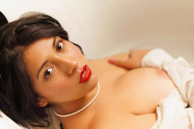 Retrato editorial con labios rojos, perlas y gesto íntimo para edición de material visual